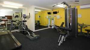 A gym with cardio machines, weightlifting equipment, and a mirror.