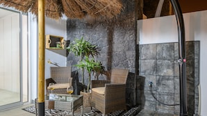 A cozy lounge area with wicker furniture, a glass table, and a potted plant.