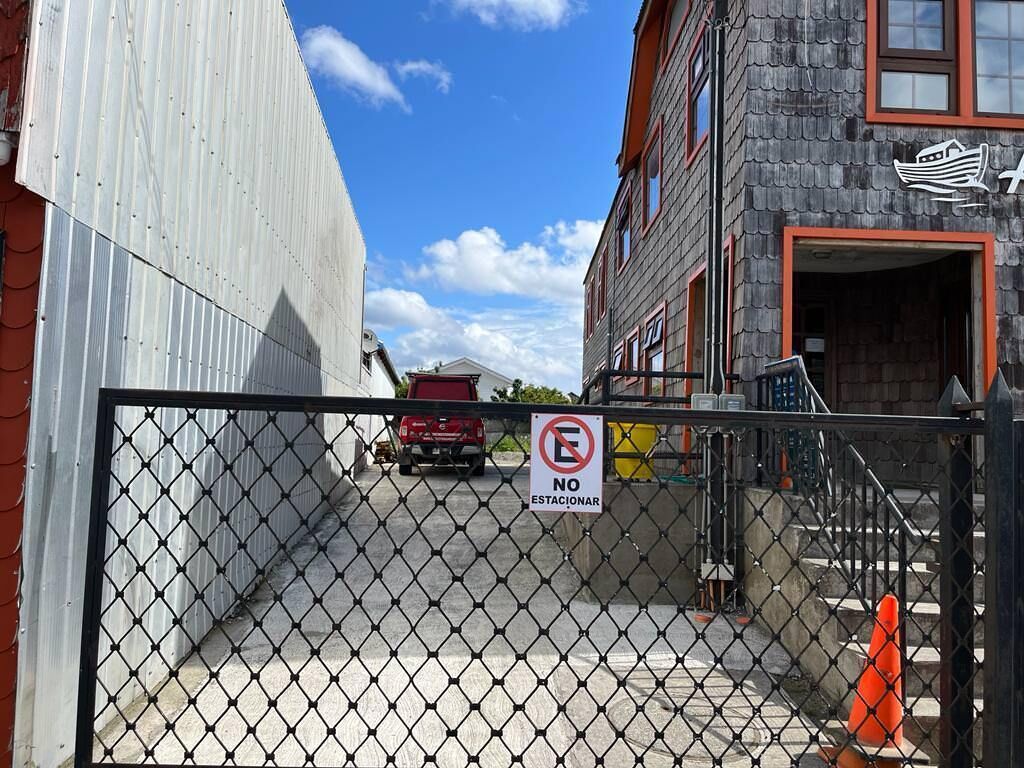 Uma área cercada com placa de proibido estacionar, uma caminhonete vermelha e um edifício com o logotipo de um navio.