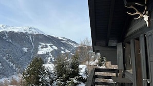 Una baita di montagna con un paesaggio innevato e un teschio di cervo appeso alla parete esterna.