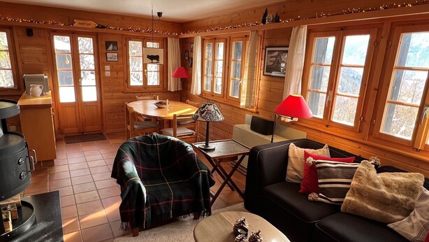 Un interno accogliente di una baita con un'area pranzo, un divano e un tavolino.