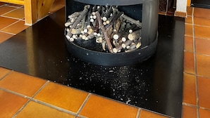 Un camino a legna con un fuoco acceso al suo interno, posizionato su un pavimento piastrellato.