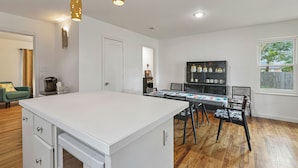 Una cocina moderna con una isla blanca, suelo de madera e iluminación colgante.
