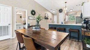 A modern kitchen with a wooden dining table, bar stools, and a kitchen island. - Vansen's Golfshores Inviting, Cozy Condo on Golf Course! (Branson)