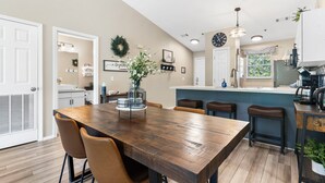 A modern kitchen with a wooden dining table, bar stools, and a kitchen island. - Vansen's Golfshores Inviting, Cozy Condo on Golf Course! (Branson)