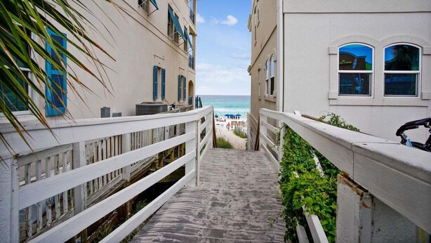 A narrow stone staircase leading to a beach, flanked by buildings with balconies and blue shutters. - 🌊Beautiful Peek of the Gulf~Pools~Walk2Beach~On the Beach🌊 (Miramar Beach)