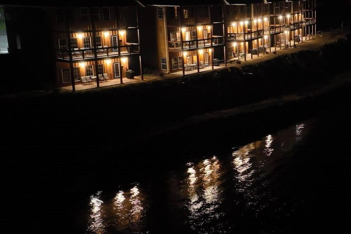 Een rij meerverdiepinggebouwen met verlichte ramen en balkons, die weerspiegeld worden in het water.