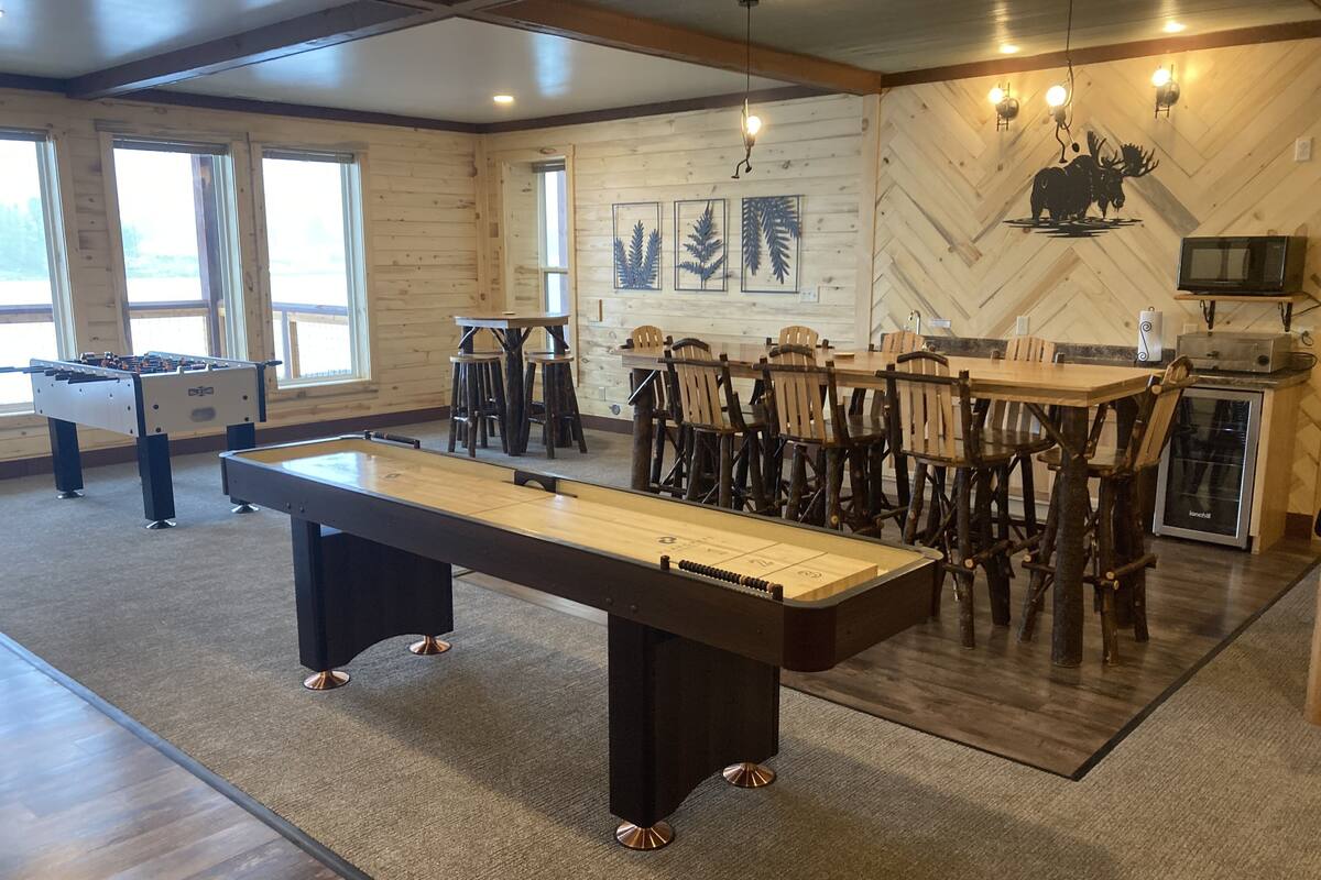 Een pooltafel in een ruimte met houten wanden, een tafelvoetbaltafel en een bar met krukken.