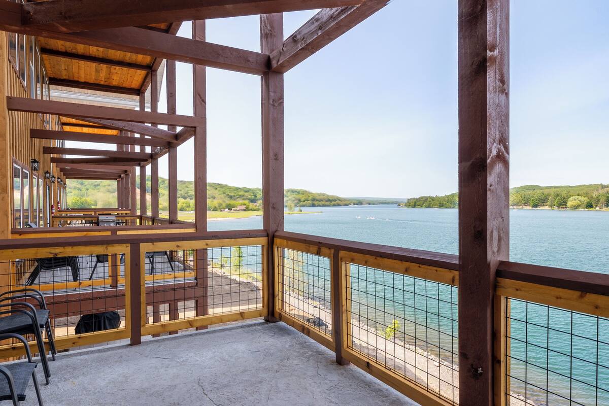 Een houten terras met uitzicht op een meer en heuvels.