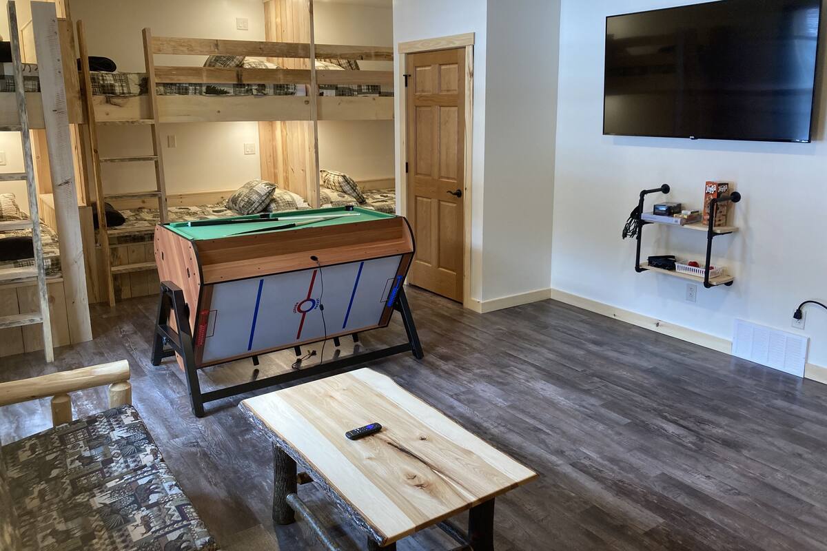 Een kamer met een pooltafel, stapelbedden, een televisie en een klein plankje met spullen.