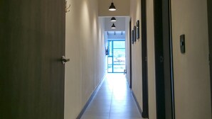 A hallway with wooden doors, pendant lighting, and a view of the outside. - Casa García Rent Home (Guatapé)