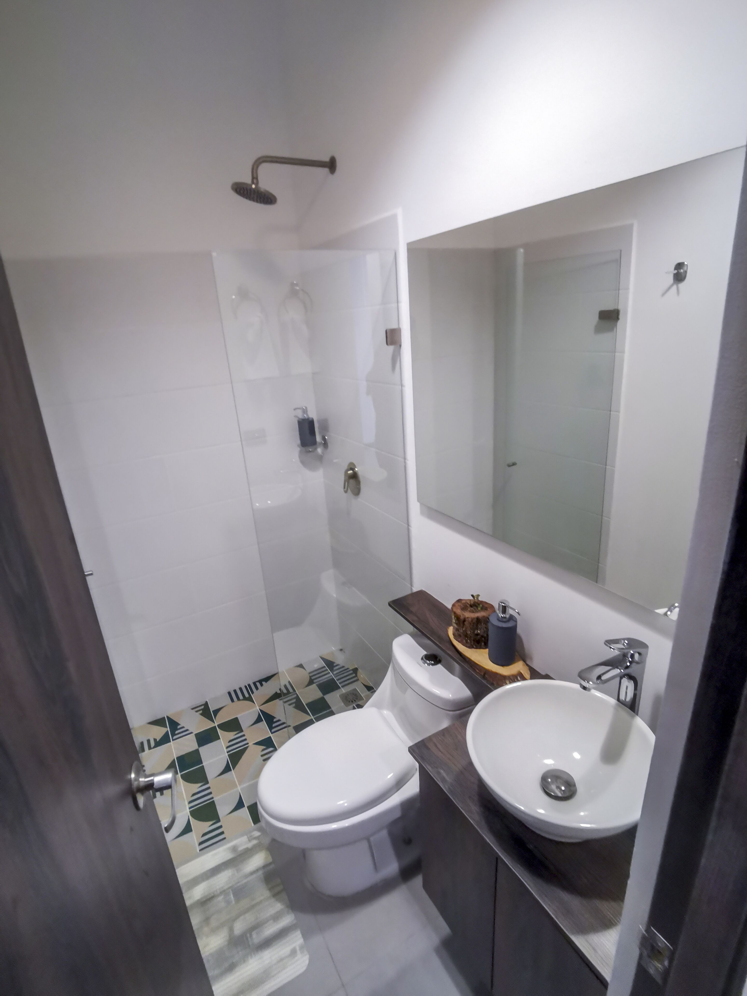 A modern bathroom with a shower, two toilets, a sink, and a mirror.