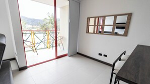 A modern room with a sliding glass door leading to a balcony, a wooden-framed mirror on the wall, and a dark wooden table. - Casa García Rent Home (Guatapé)