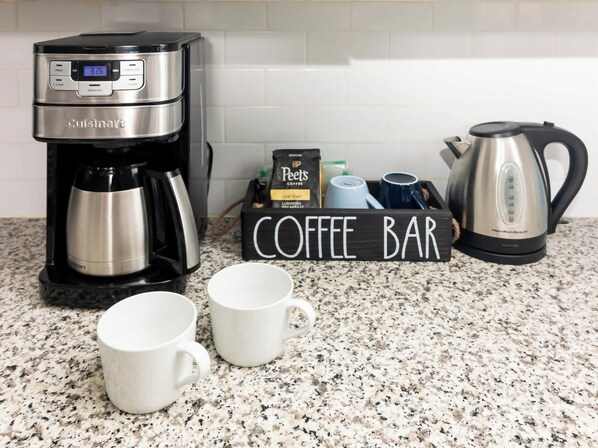 A kitchen counter with a coffee maker, a coffee bar sign, and a kettle. - Sun Bay Getaway Backyard Pool w/ Winter Rates! (Tampa)