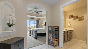 Un dormitorio con cama, ventilador de techo y vista al exterior.