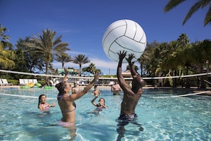 A pool area with a volleyball net, palm trees, and lounge chairs. - Seven Eagles Lavish: Water Park, Golf, Near Disney (Kissimmee)
