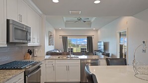 Una cocina moderna con armarios blancos, un microondas integrado y una isla grande con un fregadero.