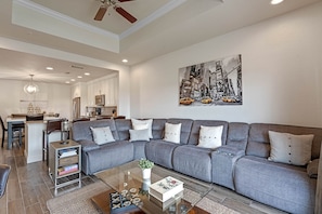 A modern living room with a gray sectional sofa, a glass coffee table, and a cityscape painting on the wall. - Seven Eagles Lavish: Water Park, Golf, Near Disney (Kissimmee)