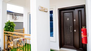 Un edificio blanco con una puerta marrón oscuro, un extintor y un letrero que dice "Rose".