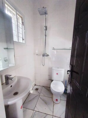 A small bathroom with a sink, toilet, and shower.