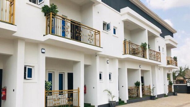 Un edificio residencial de varios pisos con balcones, un extintor y un camino de entrada pavimentado.