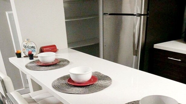 A modern kitchen with a white countertop, stainless steel appliances, and bar stools. - Luxury Apt-- 1 mile from Strip (Las Vegas)