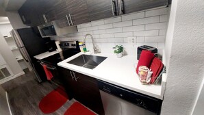 A modern kitchen with stainless steel appliances, a white countertop, and red accents. - Luxury Apt-- 1 mile from Strip (Las Vegas)
