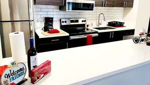 A modern kitchen with stainless steel appliances, dark wood cabinets, and a white countertop. - Luxury Apt-- 1 mile from Strip (Las Vegas)