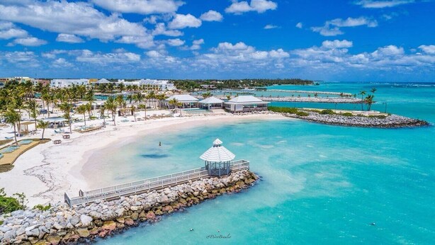 A beach resort with a white sandy beach, clear turquoise waters, and a gazebo structure.