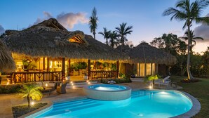 A resort with thatched-roof structures, a swimming pool, and outdoor seating areas.