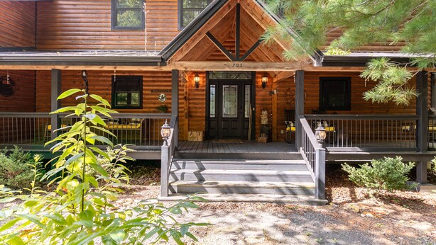 A wooden cabin with a front porch, two windows, and a door.