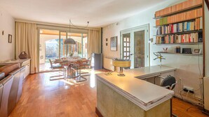 A spacious living area with a dining table, chairs, a sofa, a bookshelf, and a kitchen area with a counter. - Amazing home in Breda (Breda)