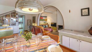A dining area with a striped tablecloth, a chandelier, and a kitchen in the background. - Amazing home in Breda (Breda)