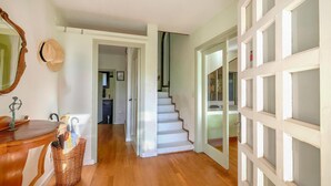 A hallway with a wooden floor, a mirror, a wicker basket, and a door leading to another room. - Amazing home in Breda (Breda)