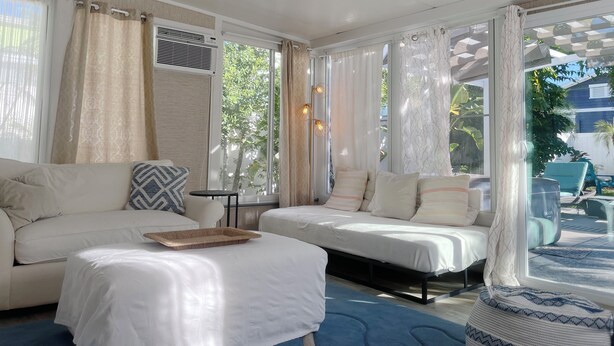 A modern room with a sofa, a bed, and a lounge area with a view of greenery outside.