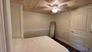 Ein Schlafzimmer mit Bett, Deckenventilator, Tür und Spiegel.