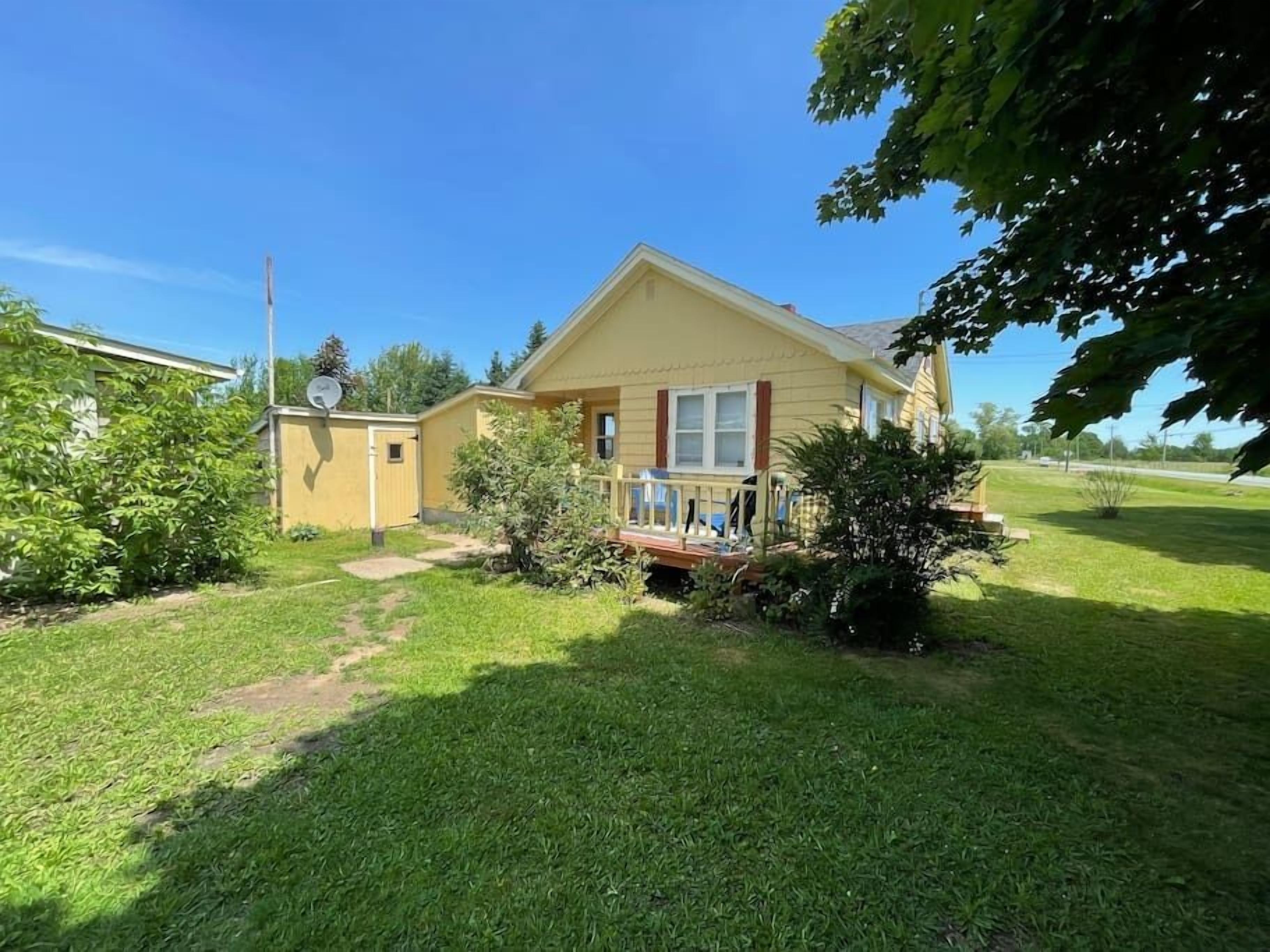 A single-story house with a front porch, a small garden, and a clear sky.