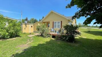 A single-story house with a front porch, a small garden, and a clear sky.
