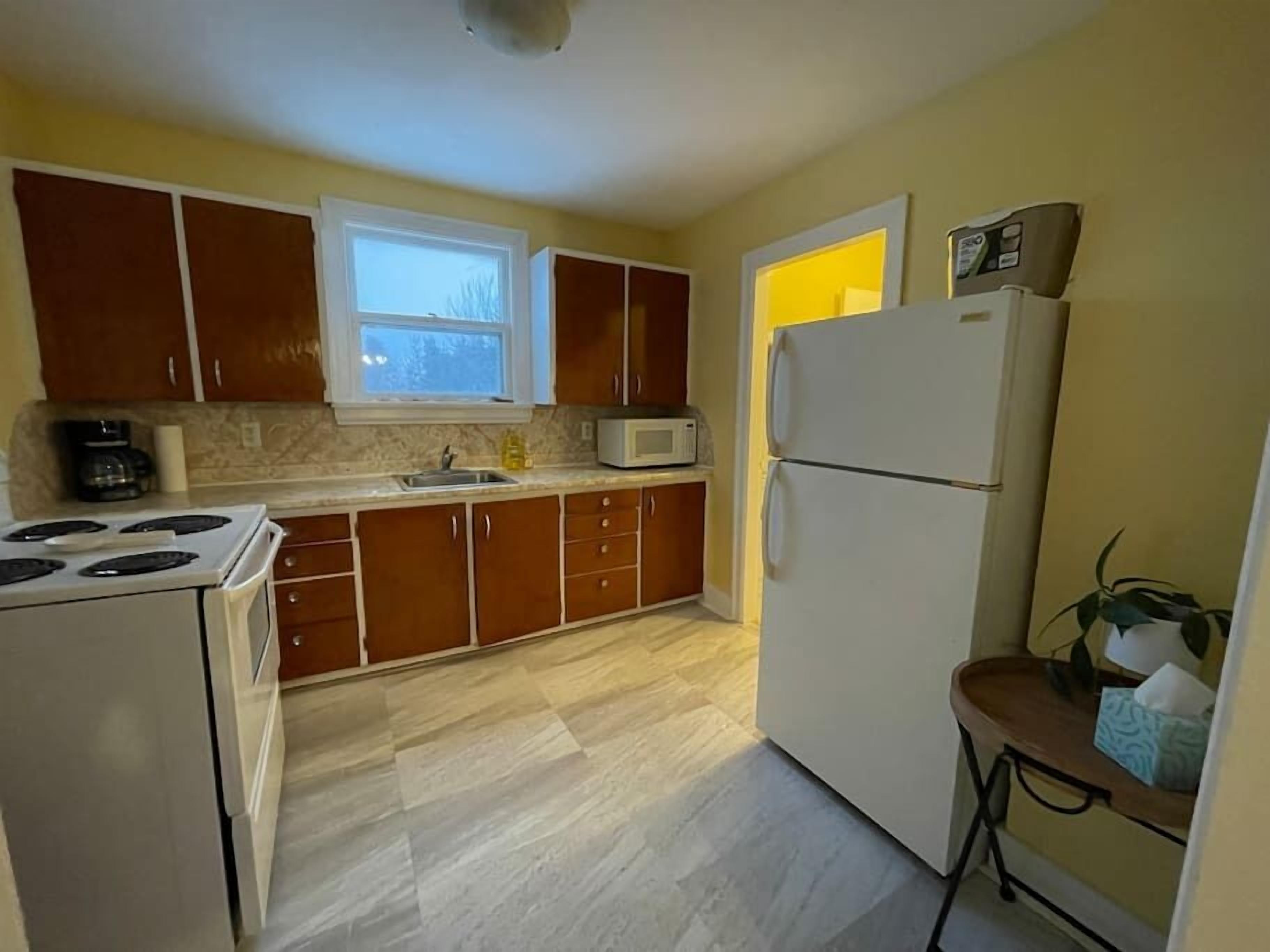 Una cocina compacta con armarios de madera, un refrigerador blanco, un microondas y una estufa.