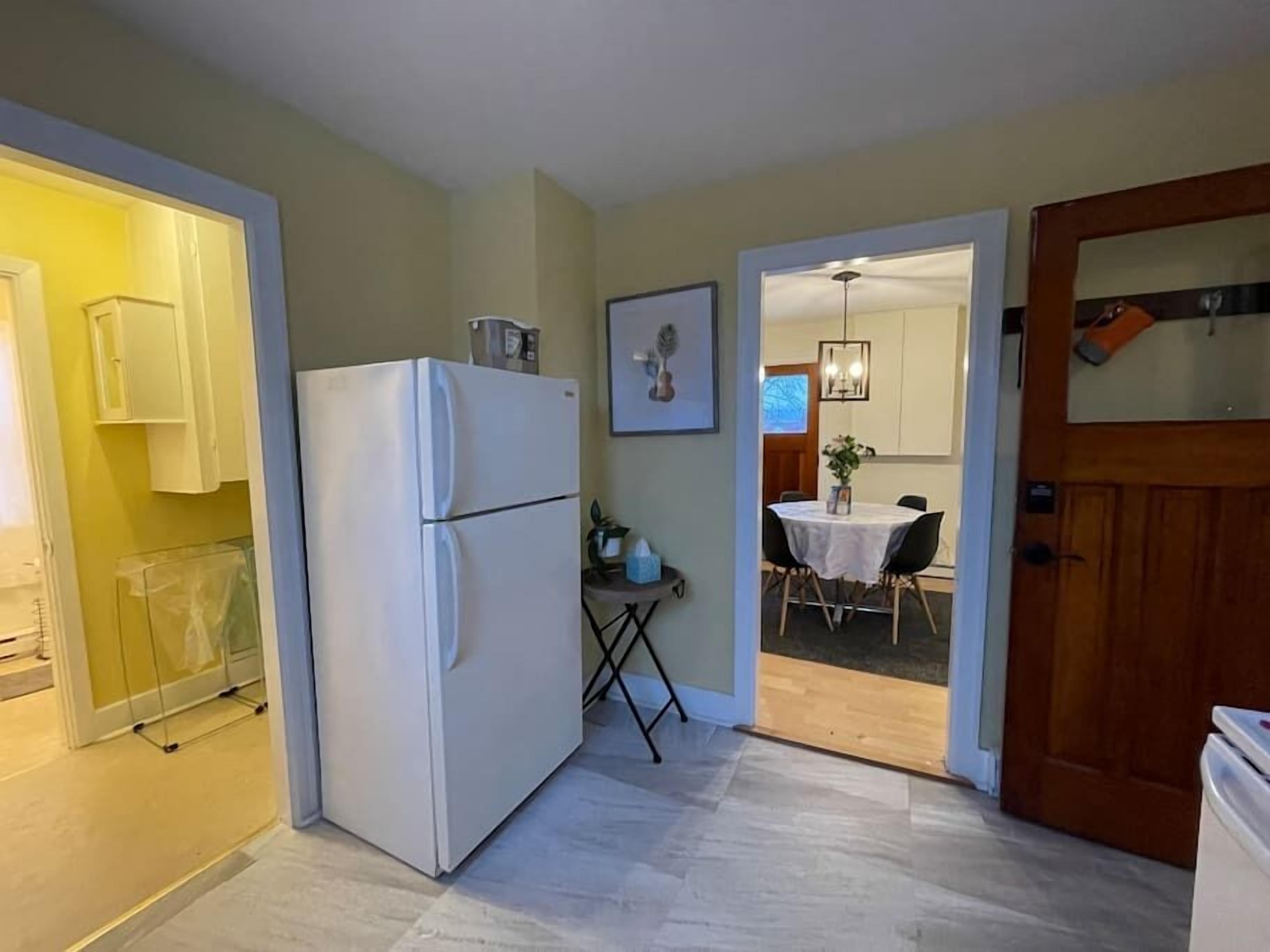 Una cocina compacta con refrigerador, una mesa de comedor con sillas y una puerta de madera.