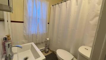 Un baño con lavamanos, inodoro y cortina de ducha blancos.