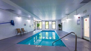 Ein Hallenbad mit klarem Wasser, einer Tiefenmarkierung von 90 Zentimetern und einigen Stühlen in der Nähe des Beckens.