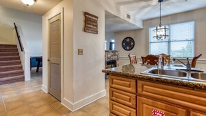 A kitchen with a stone fireplace, wooden cabinets, a granite countertop, and a large wall clock. - Owl See You 3205 - Close to Dollywood and Overlooking Gatlinburg Golf Course (Pigeon Forge)