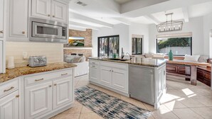 Une cuisine moderne avec des meubles blancs, un four à micro-ondes encastré et un plan de travail en granit.