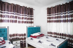 Un dormitorio con dos camas, un aparador y cortinas estampadas.