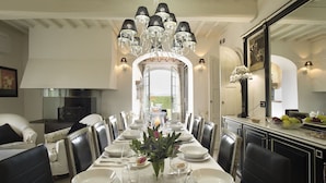A dining room with a long table set for a meal, a chandelier, and a view through an open archway. - Private Villa with hot tub, sauna, A/C, private pool, WIFI, TV, patio, close to Greve In Chianti (Tavarnelle Val Di Pesa)