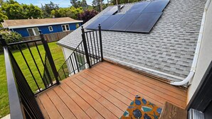 A deck with a railing, solar panels on the roof, and a house in the background. - Cozy Private Retreat Near Downtown + Hospital (Martinez)