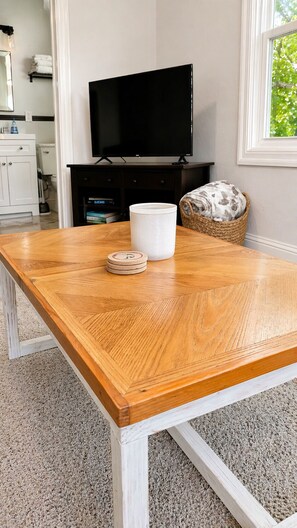 A wooden dining table with a white base, a white ceramic mug, and a wooden coaster.