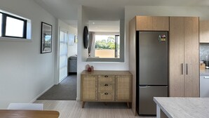 A modern kitchen with a wooden cabinet, a stainless steel refrigerator, and a marble countertop. - Little Break Tahunanui - 5 minutes from beach (Nelson)