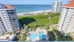 Et hotel med pool, omgivet af frodig vegetation og udsigt til strand og hav.